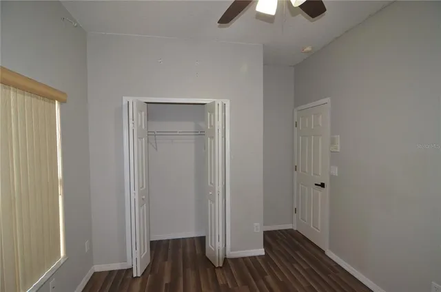 an empty room with wooden floor fan and windows