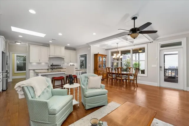 a living room with furniture kitchen view and a wooden floor