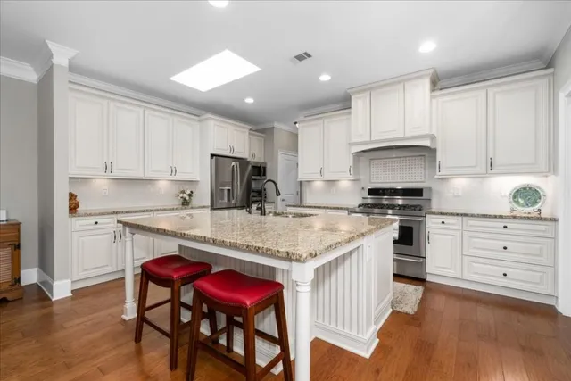 a kitchen with stainless steel appliances granite countertop a white cabinets and wooden floor