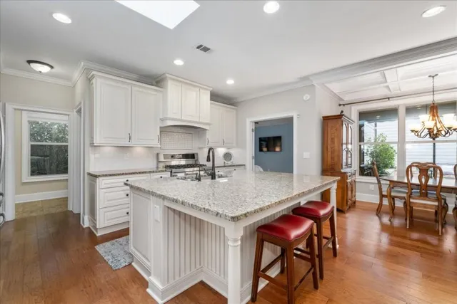 a kitchen with stainless steel appliances granite countertop a stove a sink dishwasher a dining table and chairs with wooden floor