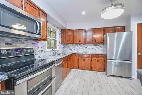 a kitchen with stainless steel appliances granite countertop a refrigerator and a stove top oven