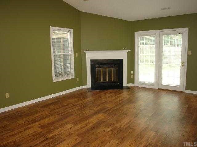 4412 Roller Court Raleigh, NC 27604 - Photo 4 of 12 an empty room with wooden floor fireplace and windows