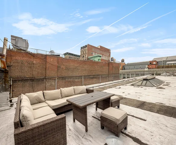 a view of roof deck with couches and sky view