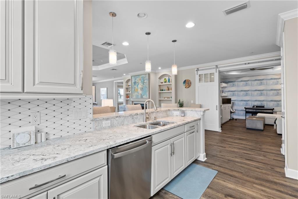 9684 Montelanico Loop, Unit 101 Naples, FL 34119 - Photo 12 of 49 Kitchen with kitchen peninsula, stainless steel dishwasher, sink, pendant lighting, and white cabinetry