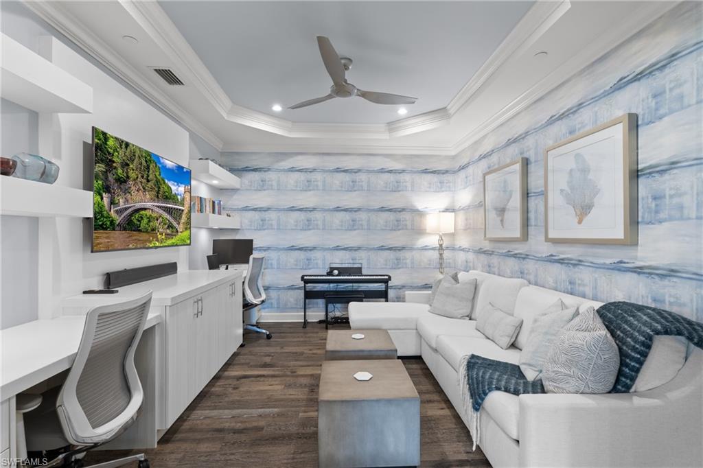 9684 Montelanico Loop, Unit 101 Naples, FL 34119 - Photo 13 of 49 Living room with a raised ceiling, crown molding, ceiling fan, built in desk, and dark hardwood / wood-style flooring