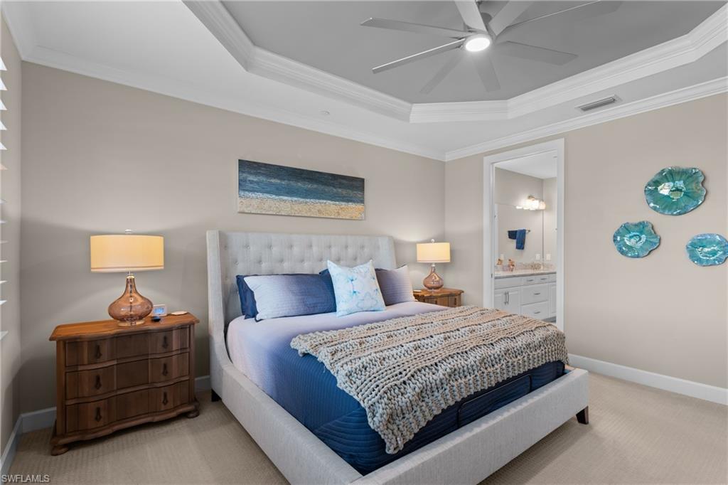 9684 Montelanico Loop, Unit 101 Naples, FL 34119 - Photo 15 of 49 Bedroom with ensuite bathroom, a raised ceiling, ceiling fan, ornamental molding, and light colored carpet