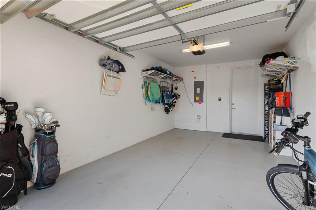 9684 Montelanico Loop, Unit 101 Naples, FL 34119 - Photo 29 of 49 Garage featuring electric panel and a garage door opener