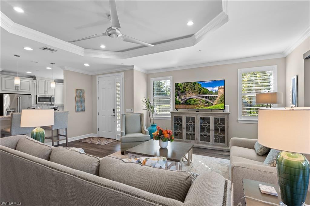 9684 Montelanico Loop, Unit 101 Naples, FL 34119 - Photo 4 of 49 Living room featuring crown molding, dark wood-type flooring, ceiling fan, and a healthy amount of sunlight