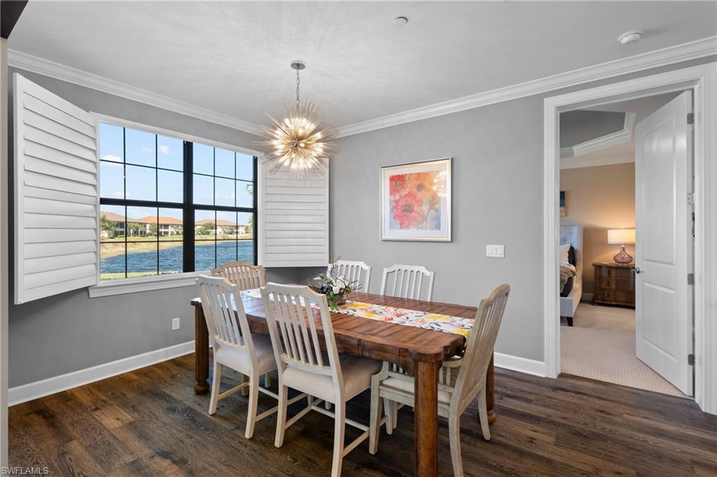 9684 Montelanico Loop, Unit 101 Naples, FL 34119 - Photo 5 of 49 Dining space with a water view, ornamental molding, dark wood-type flooring, and a chandelier