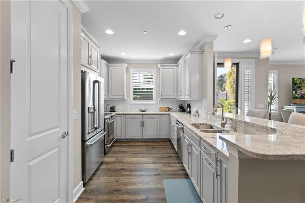 9684 Montelanico Loop, Unit 101 Naples, FL 34119 - Photo 10 of 49 Kitchen with stainless steel appliances, sink, decorative light fixtures, dark hardwood / wood-style floors, and white cabinetry