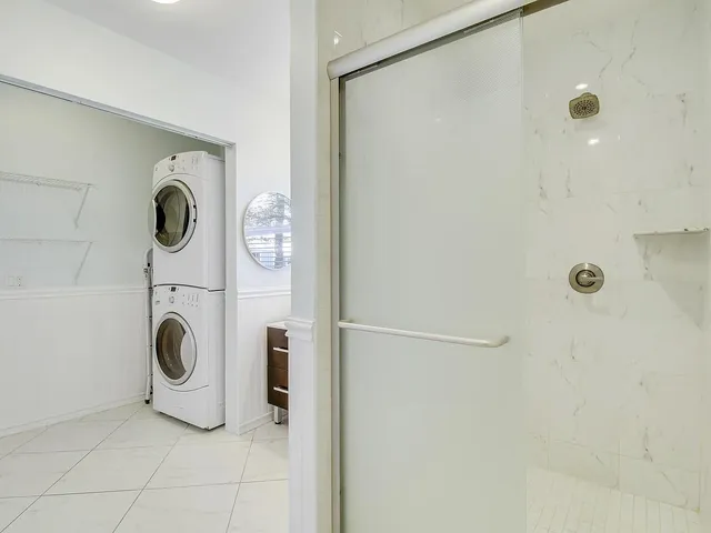 a bathroom with a granite countertop shower a mirror and clock on the wall