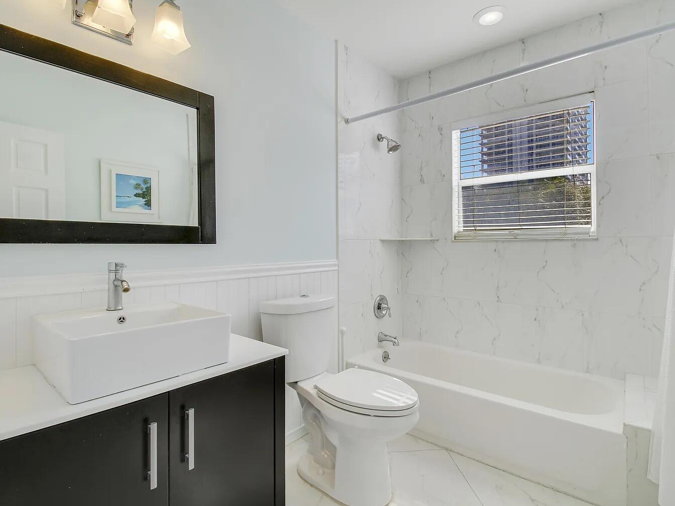 1310 Manor Drive Singer Island, FL 33404 - Photo 20 of 25 a bathroom with a toilet a sink a mirror and bathtub