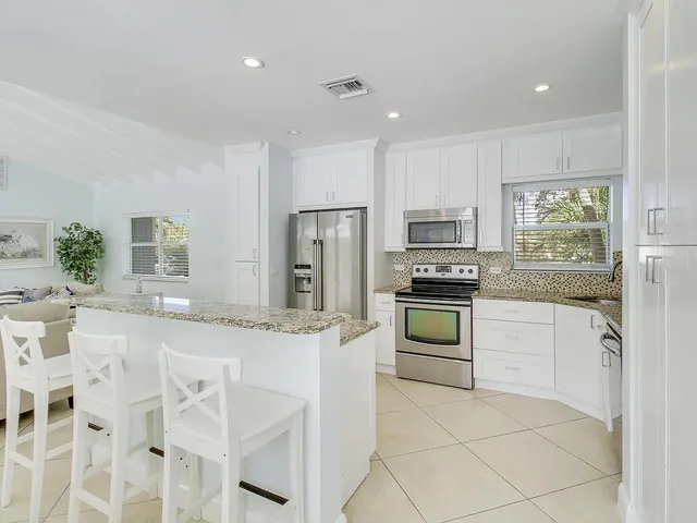 a kitchen with granite countertop white cabinets and stainless steel appliances