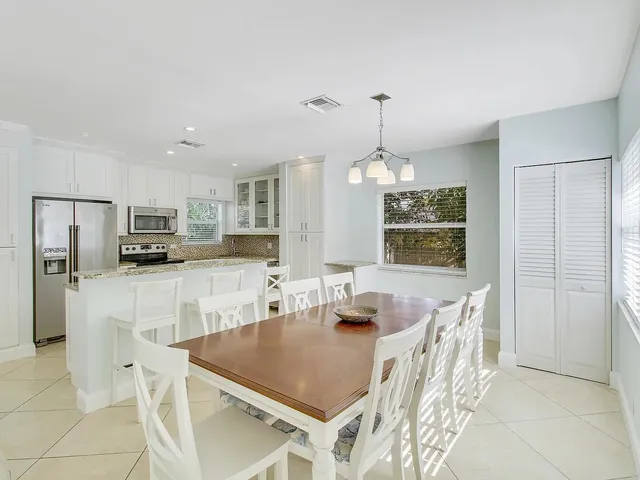 a kitchen with stainless steel appliances kitchen island granite countertop a refrigerator a stove a sink a dining table and chairs