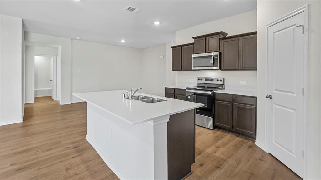1953 Freeman Street Tyler, TX 75704 - Photo 4 of 32 Contemporary kitchen with wood-finish flooring, white quartz countertops, stainless steel appliances, dark wood cabinetry, and recessed lighting
