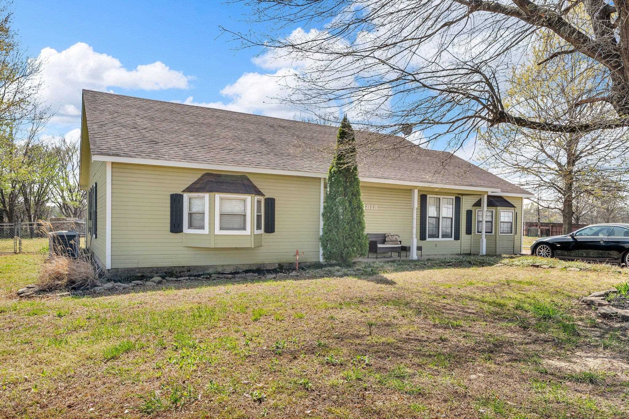 View of front of property featuring a front yard, a shingled roof, and fence
