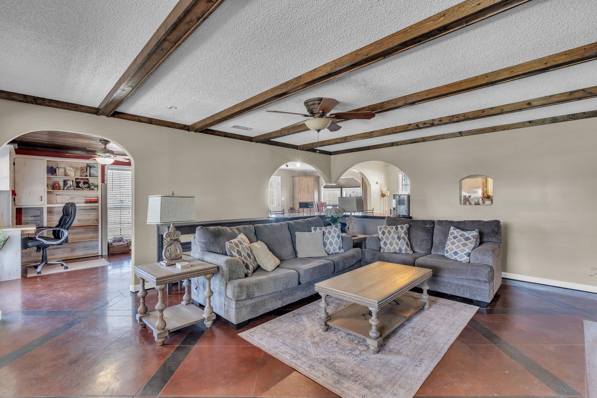 Great Room featuring arched walkways, a textured ceiling, and a ceiling fan.