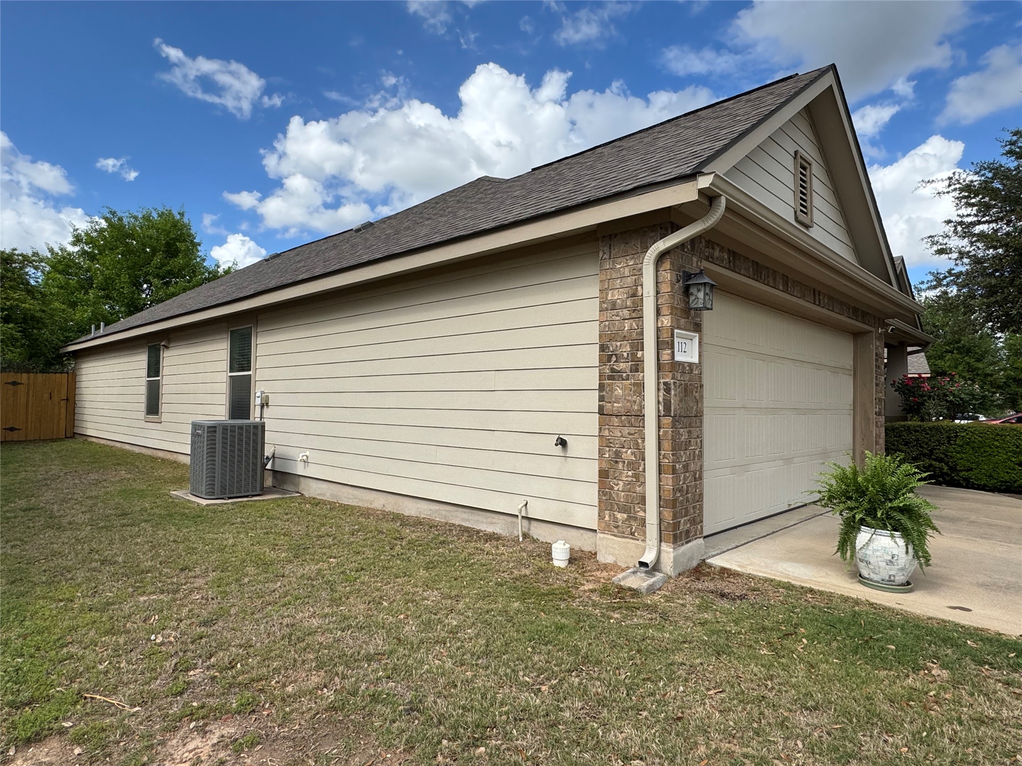 112 Eagle Owl Loop Leander, TX 78641 - Photo 28 of 34 View of property exterior featuring roof with shingles, brick siding, driveway, and an attached garage
