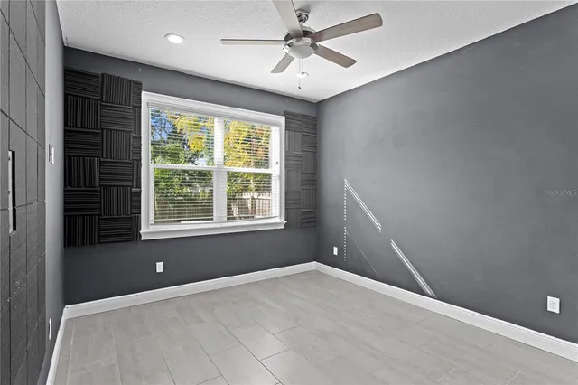 an empty room with a window and a fan