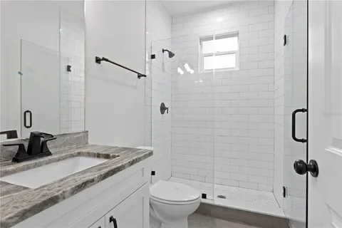 a bathroom with a granite countertop sink a toilet and shower