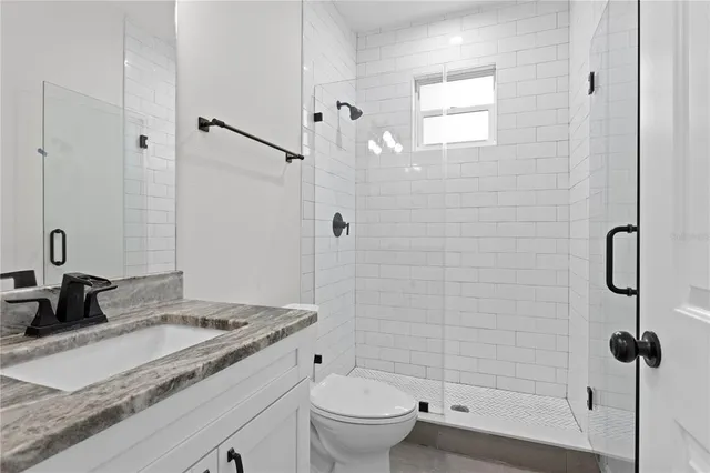 a bathroom with a granite countertop sink a toilet and shower