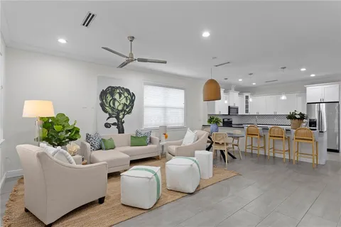 a living room with couches a fireplace with kitchen view