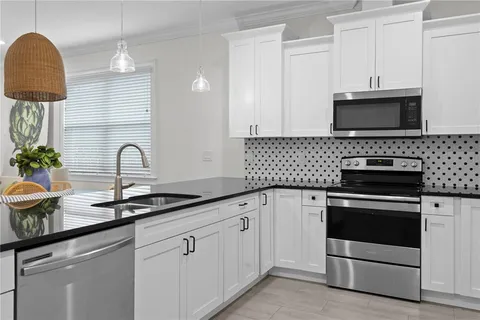 a kitchen with white cabinets and appliances