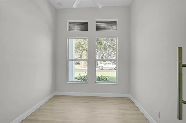 an empty room with wooden floor and windows