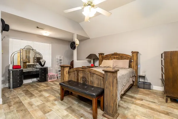 a bedroom with a bed a mirror and a flat tv screen on the dresser
