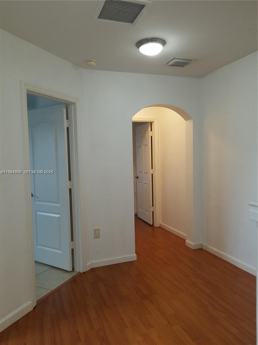 12902 Southwest 30th Street, Unit 133 Miramar, FL 33027 - Photo 11 of 16 an empty room with wooden floor and mirror