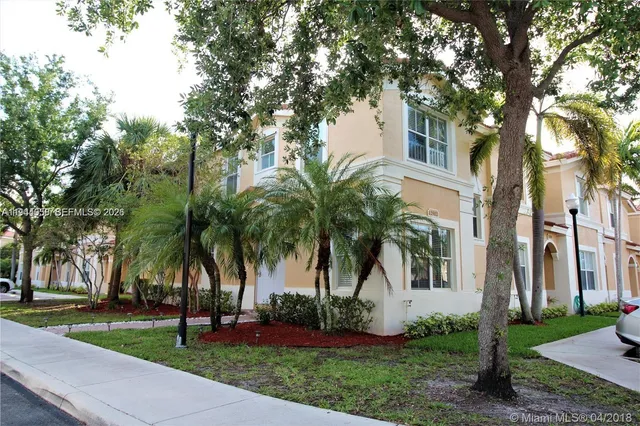 a view of a white house with a big yard and palm trees