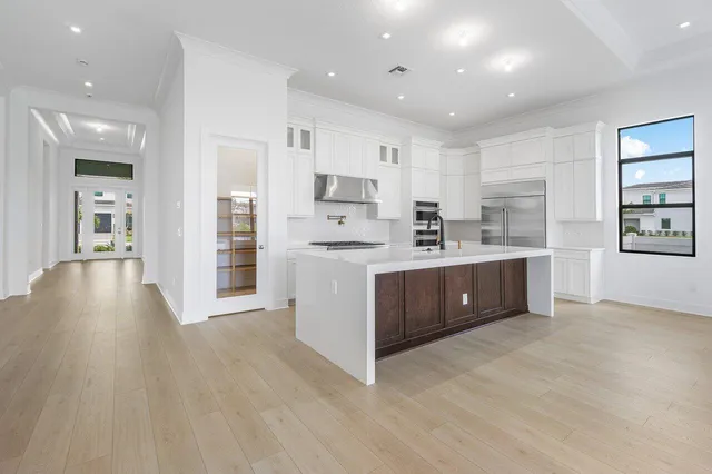 a large kitchen with stainless steel appliances granite countertop a large counter top a sink and a refrigerator