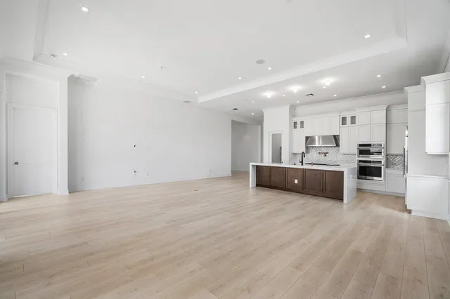 a view of a kitchen with kitchen island a sink wooden floor and stainless steel appliances