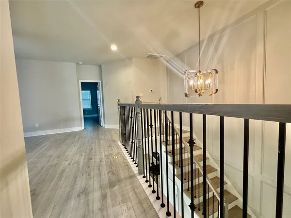 a view of a hallway with wooden floor and stairs