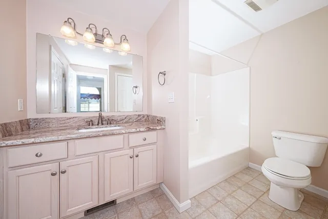 a bathroom with a granite countertop sink a toilet and a mirror