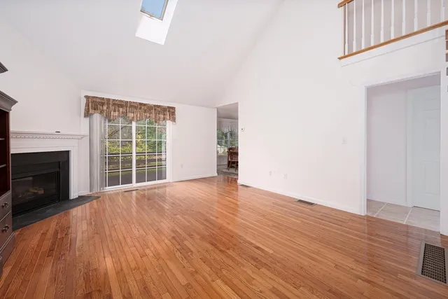an empty room with wooden floor fireplace and windows