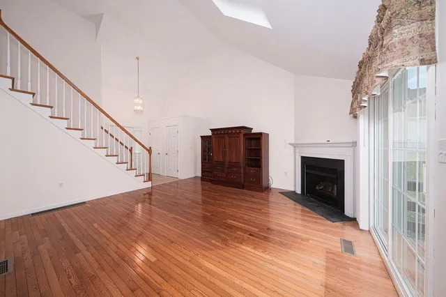 a view of an empty room with wooden floor and a fireplace
