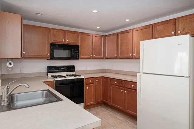 a kitchen with stainless steel appliances granite countertop a refrigerator stove a sink dishwasher and microwave with wooden cabinets