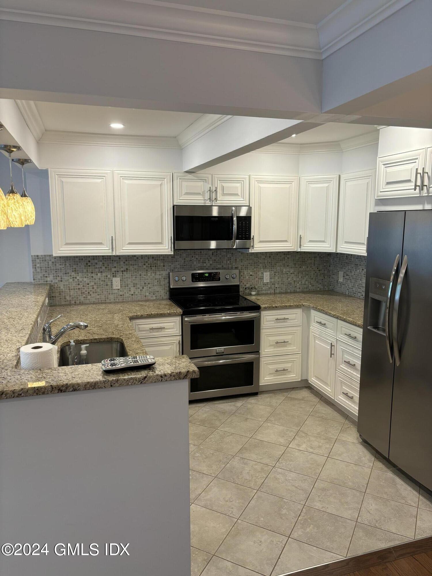 1465 East Putnam Avenue, Unit 306 Riverside, CT 06878 - Photo 3 of 13 a kitchen with stainless steel appliances granite countertop a stove a sink and a refrigerator