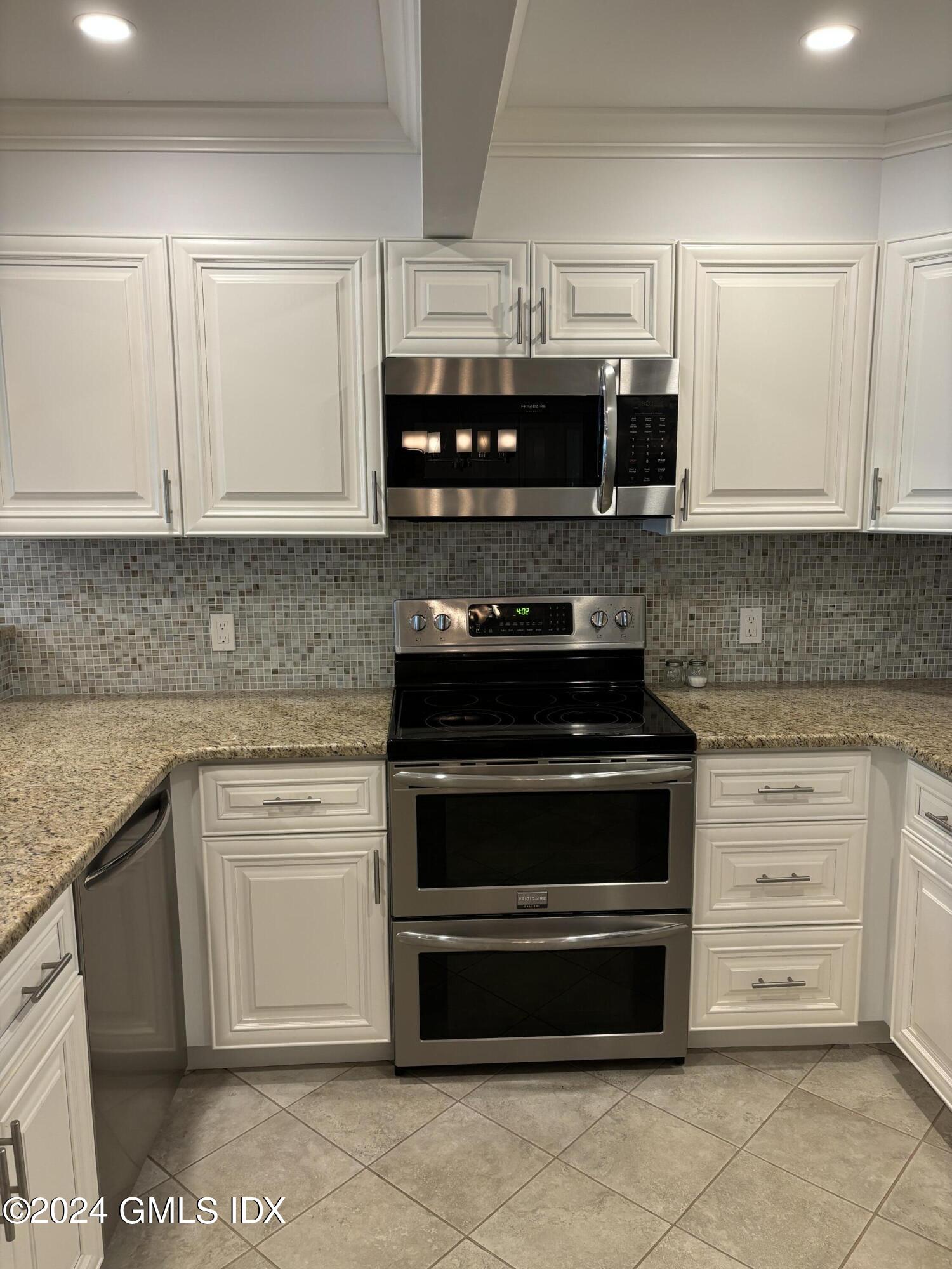 1465 East Putnam Avenue, Unit 306 Riverside, CT 06878 - Photo 4 of 13 a kitchen with stainless steel appliances granite countertop a stove and white cabinets