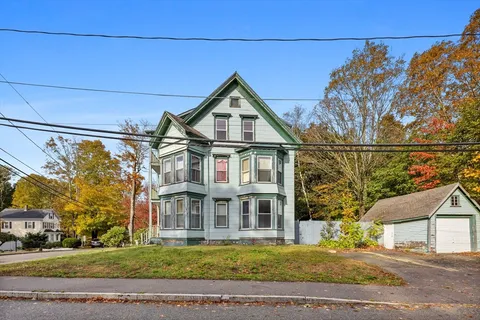 a view of a big house with a big yard and large trees