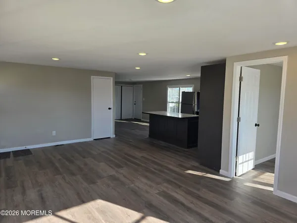 a kitchen with stainless steel appliances granite countertop a refrigerator a sink dishwasher a stove and a dining table with wooden floor