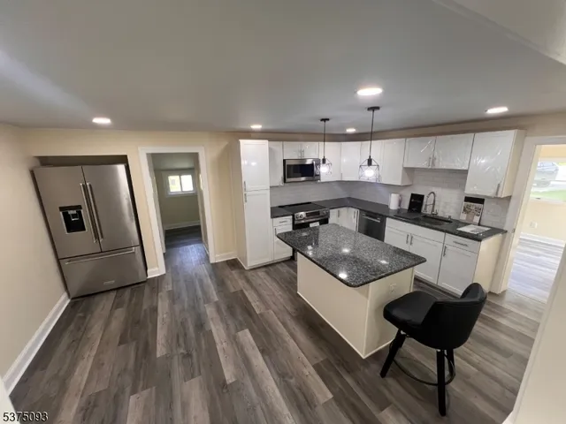 a kitchen with stainless steel appliances granite countertop a refrigerator a sink dishwasher and a stove with wooden floor