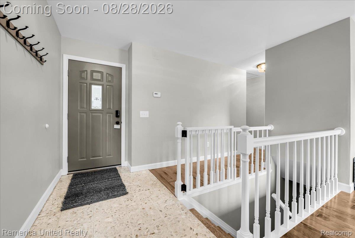 3687 Van Amberg Road Brighton, MI 48114 - Photo 16 of 56 Entryway featuring a panel door with decorative glass, tiled flooring, wood-finish flooring, and white banister
