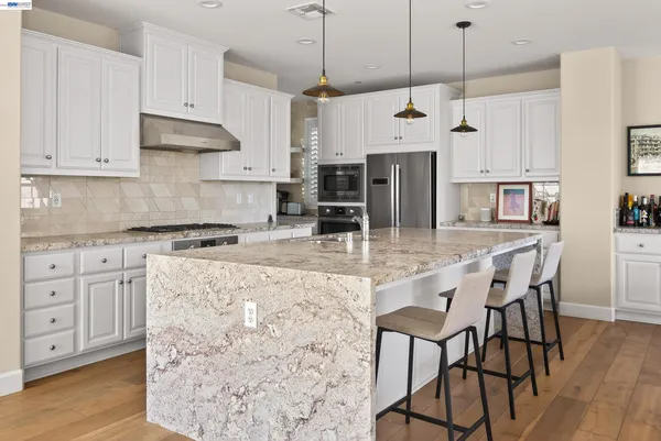 a kitchen with stainless steel appliances granite countertop a kitchen island a stove and a cabinets