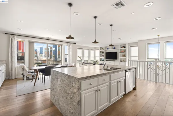 a kitchen with stainless steel appliances granite countertop a stove a sink dishwasher and a refrigerator with wooden floor