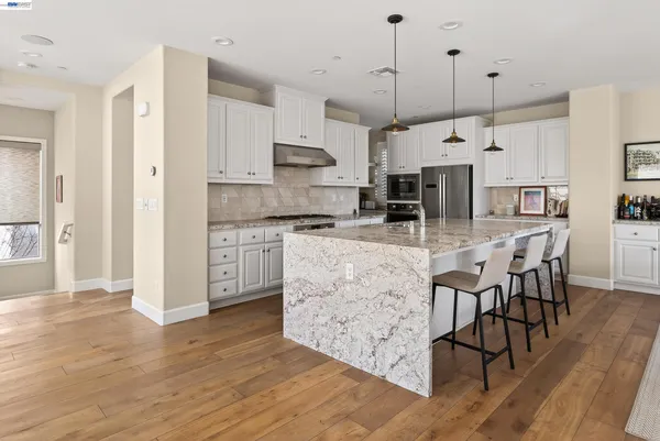 a kitchen with granite countertop white cabinets and stainless steel appliances