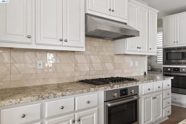 a kitchen with granite countertop a sink stove and refrigerator