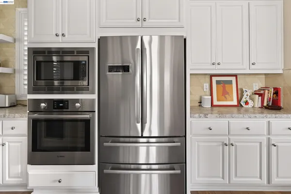 a kitchen with granite countertop white cabinets and stainless steel appliances