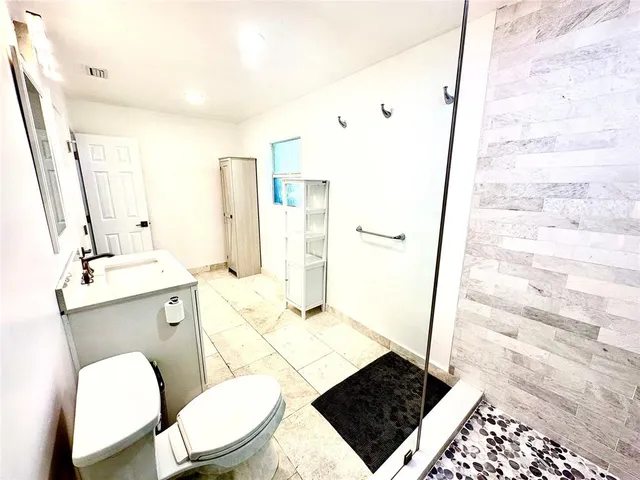 a bathroom with a sink a toilet a mirror and shower